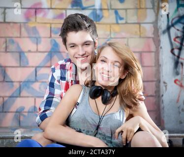 Allemagne, Berlin, Portrait of teenage couple sitting on stairs, smiling Banque D'Images