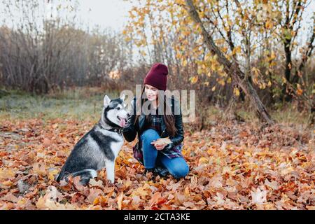 Belle jeune femme jouant avec son chien dans le parc d'automne. Banque D'Images