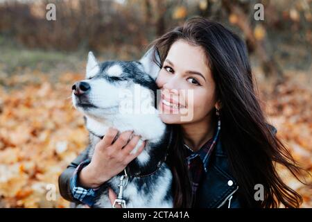 Une femme heureuse embrasse son chien husky dans un parc d'automne. Banque D'Images