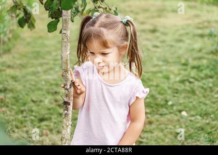 petite fille près d'un jeune arbre dans la nature. montre l'intérêt pour la nature Banque D'Images