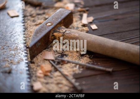Vieux marteau d'époque, scie à bois, clous et sciure sur un fond en bois, gros plan, foyer sélectif Banque D'Images