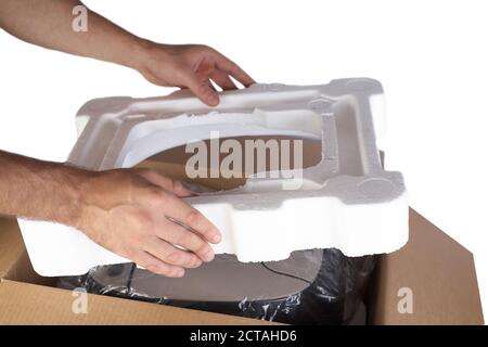 Emballage des marchandises dans une boîte en carton avec du matériau en mousse de polystyrène pour le transport sécuritaire des marchandises. Isolé sur fond blanc. Les mains de l'homme sont l'emballage de la goo Banque D'Images