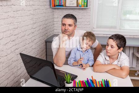 Père travaille avec des enfants sur un ordinateur portable au bureau à domicile. Travailler à domicile Banque D'Images