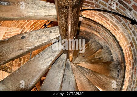 Vue sur un vieux escalier en colimaçon en bois dans une tourelle circulaire en brique dans une ancienne tour d'église médiévale en brique. Banque D'Images