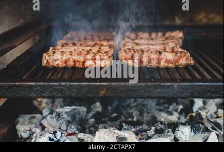 Griller de la viande sur un barbecue au charbon chaud. Préparation, cuisson de cafevcici, kebabs, saucisse de campagne sur barbecue au charbon de bois dans la cheminée extérieure. Tr Banque D'Images