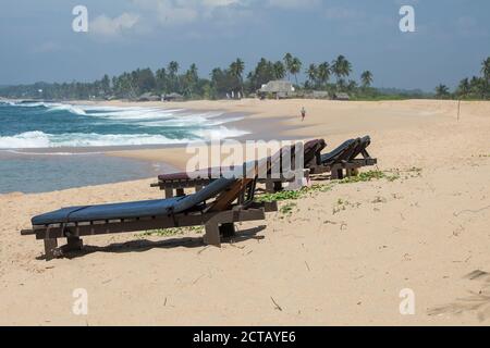 Chaises longues en bois sur une plage tropicale Banque D'Images