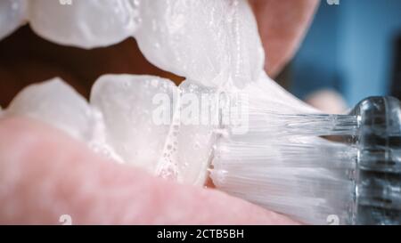 Gros plan extrême Macro prise de vue d'une personne qui se brosse les dents blanches. Le dentifrice blanchissant est utilisé sur une brosse à dents manuelle en cours d'utilisation. Bouche naturelle avec P Banque D'Images