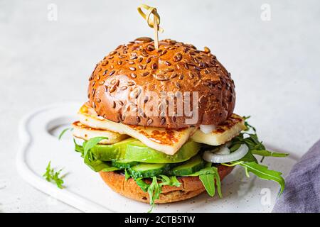 Hamburger halloumi frit avec des quartiers d'avocat et des arugula. Concept de cuisine végétarienne. Banque D'Images