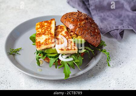 Hamburger halloumi frit avec des quartiers d'avocat et des arugula. Concept de cuisine végétarienne. Banque D'Images