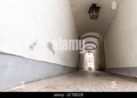 Chemin de rue intérieur pavé et étroit de la rue urbaine dans la vieille ville européenne. Allée sombre vintage avec lanterne et mur gris. Personne n'a vue sur la ville Banque D'Images