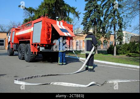 Pompier a mis les tuyaux en place, un autre vérifiant une pompe à eau Banque D'Images