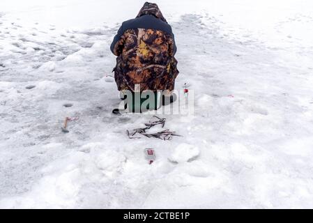 Homme pêche sur glace sur un lac gelé. Vacances d'hiver et concept de personnes. Pêche d'hiver. Banque D'Images