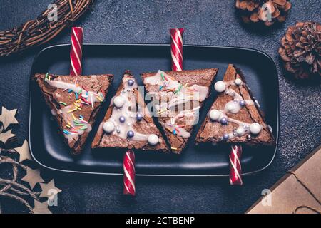 Brownies d'arbres de Noël avec canne à sucre et glaçage, fond sombre. Concept de la nourriture de Noël. Banque D'Images