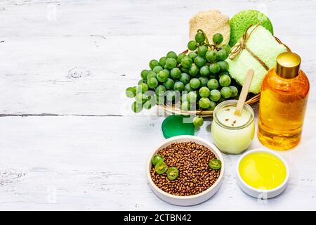 Accessoires de spa naturels et raisins verts. Des ingrédients frais pour des soins personnels sains et confortables. Arrière-plan en bois blanc, espace de copie Banque D'Images