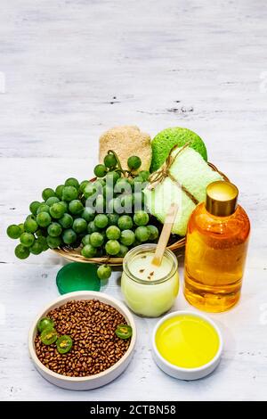 Accessoires de spa naturels et raisins verts. Des ingrédients frais pour des soins personnels sains et confortables. Fond en bois blanc, gros plan Banque D'Images