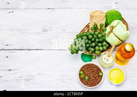 Accessoires de spa naturels et raisins verts. Des ingrédients frais pour des soins personnels sains et confortables. Arrière-plan en bois blanc, vue du dessus Banque D'Images