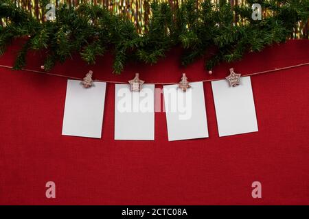 Maquette du nouvel an avec 4 feuilles blanches vierges pour en écrivant le numéro de l'année ou en lettres sur un fond rouge avec décorations de noël Banque D'Images