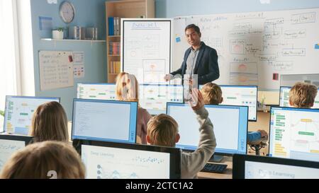Cours élémentaire : l'enseignant utilise le tableau blanc numérique interactif, explique la leçon à divers groupes d'enfants intelligents. Les enfants lève la main et le tuteur Banque D'Images