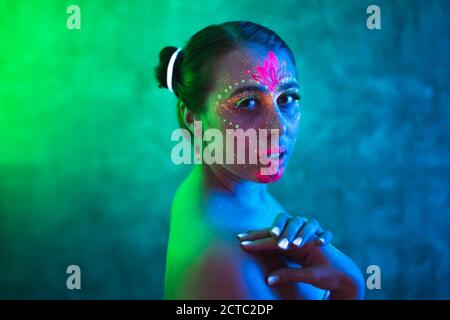 Belle femme avec art du corps luminescent lumière ultraviolette. Concept ethnique, ésotérique et fantaisie. Portrait de belle personne peint en fluorescent Banque D'Images