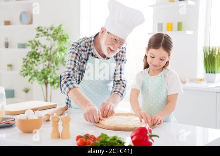 Portrait de gaie gentille gaie heureux grand-père à cheveux gris enseignant petit-enfant apprendre à cuisiner savoureuse recette de plat délicieux cuisine nationale saine Banque D'Images