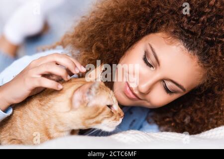 Foyer sélectif de la jeune femme à cheveux rouges regardant tabby chat à la maison Banque D'Images
