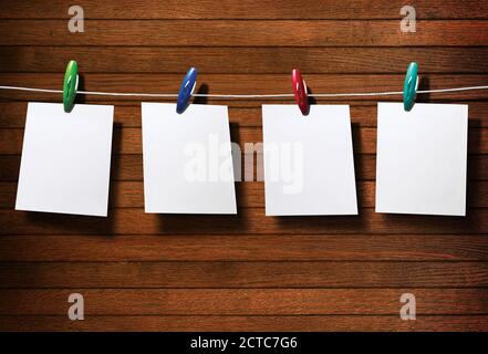 Papier photo blanc et pinces à linge sur une clôture en bois Banque D'Images