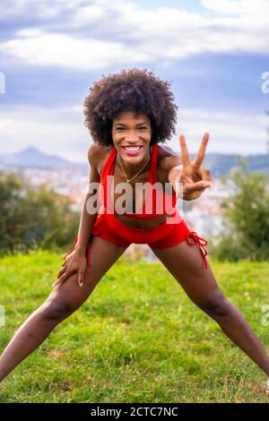 Photo verticale d'une belle femme hispanique noire portant des vêtements de sport et montrant le signe de la paix Banque D'Images