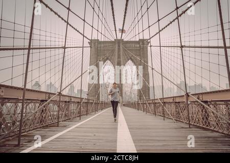 Femme pratiquant le jogging sur le pont de Brooklyn Banque D'Images