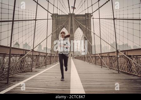 Femme pratiquant le jogging sur le pont de Brooklyn Banque D'Images