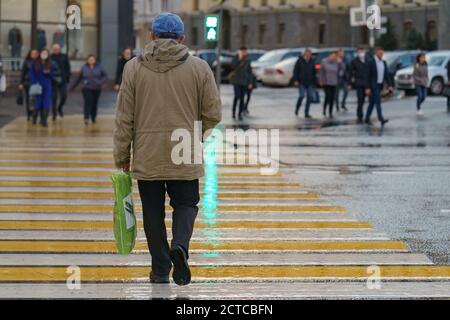 Moscou, Russie - 10 septembre 2020 : rue de passage d'homme mature. Vue arrière/arrière. Témoin vert du feu de stop. Foule de gens de l'autre côté de la route. Banque D'Images