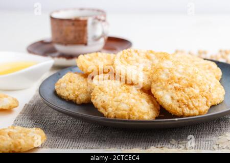 Biscuits japonais traditionnels aux chips de riz avec sauce au miel et au soja sur une assiette en céramique bleue et une tasse de café sur fond de bois blanc. Vue latérale, Banque D'Images