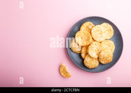 Le riz japonais traditionnel croustilles biscuits avec du miel et de la sauce soja sur fond rose pastel. Vue de dessus, plat, espace de copie. Banque D'Images