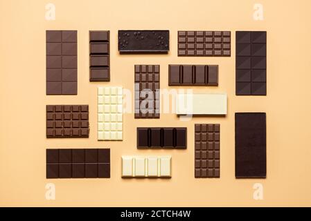 Assortiment de barres de chocolat isolé sur fond beige. Vue de dessus de la collection de chocolat fin, sombre, lait, et blanc. Assortiment de chocolat au four. Banque D'Images