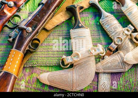 Khanjars et fusils exposés au marché du vendredi des armes à feu à Nizwa, en Oman Banque D'Images