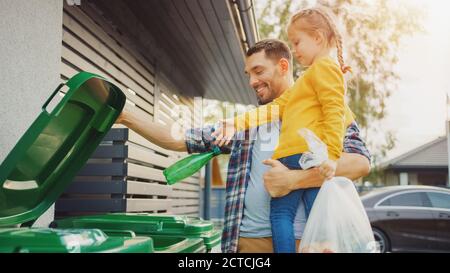 Père tenant une jeune fille et jeter une bouteille vide et des déchets alimentaires dans la corbeille. Ils utilisent des poubelles correctes car cette famille est en cours de tri Banque D'Images