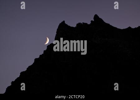 Lune en croissant avec silhouette de crête de montagne contre ciel clair la nuit Banque D'Images