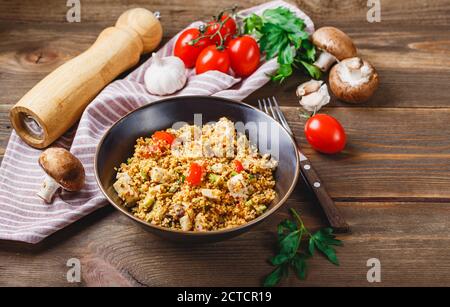 Couscous à la dinde, tomates, champignons et avocat sur fond de bois. Plat traditionnel au Moyen-Orient et au régio méditerranéen Banque D'Images