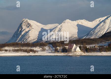 Les sommets enneigés de la montagne sont la toile de fond de la petite église de Trondenes à Harstad, en Norvège Banque D'Images