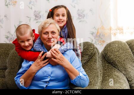 Grand-mère et petits-enfants assis ensemble sur un canapé dans la salle de séjour Banque D'Images