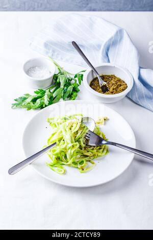 Des nuddles de Zucchini sains avec du pesto sur fond blanc Banque D'Images