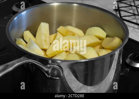 Les pommes se pichent dans une casserole sur une cuisinière. Couleur sélective Banque D'Images