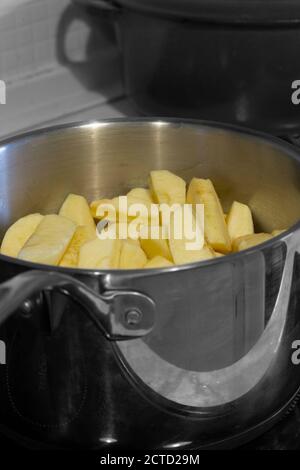 Les pommes se pichent dans une casserole sur une cuisinière. Couleur sélective Banque D'Images