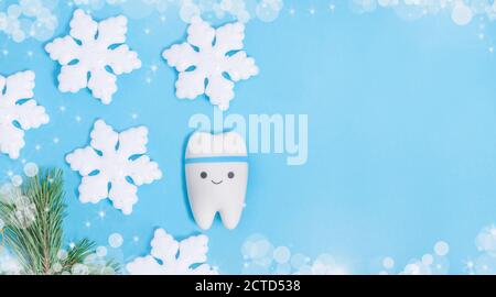 Baner pour la dentisterie pour Noël et le nouvel an avec un modèle de dent sur fond bleu avec un décor de flocons de neige avec espace de copie. Banque D'Images