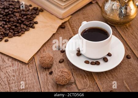 café frais préparé dans une cafetière (traditionnelle turque) boisson du matin dans une tasse blanche à côté des boules de chocolat Banque D'Images