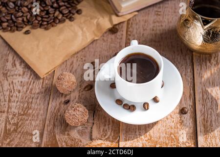 café frais préparé dans une cafetière (traditionnelle turque) boisson du matin dans une tasse blanche à côté des boules de chocolat Banque D'Images