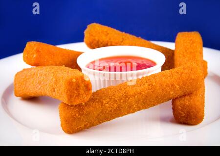 Bâtonnets de fromage panés à la sauce rouge, sur une assiette blanche. Banque D'Images