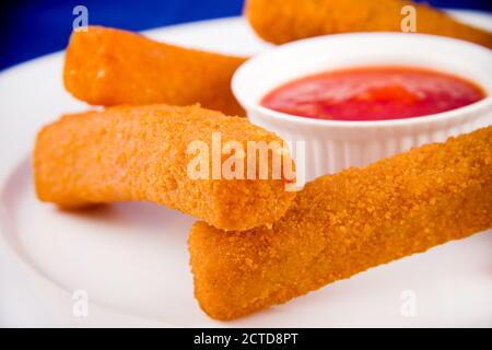 Bâtonnets de fromage panés à la sauce rouge, sur une assiette blanche. Banque D'Images