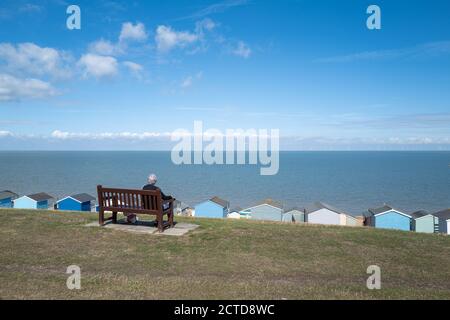 Whitstable, Royaume-Uni - 6 septembre 2020 UNE dame senior est assise sur un banc donnant sur la mer à Tankerton, Whtistable. Elle a un chien avec elle. Il y a une ligne de be Banque D'Images