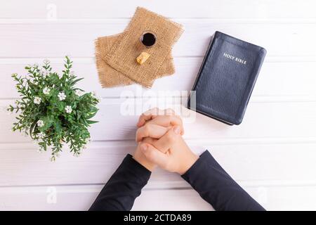 Jeune femme priant et prenant la communion - le vin et les symboles du pain de Jésus Christ sang et corps avec la Sainte Bible. Pâque de Pâques et Seigneur su Banque D'Images