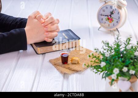 Jeune femme priant et prenant la communion - le vin et les symboles du pain de Jésus Christ sang et corps avec la Sainte Bible. Pâque de Pâques et Seigneur su Banque D'Images